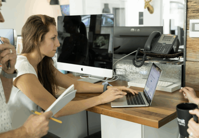 Three people circled around a computer in an office